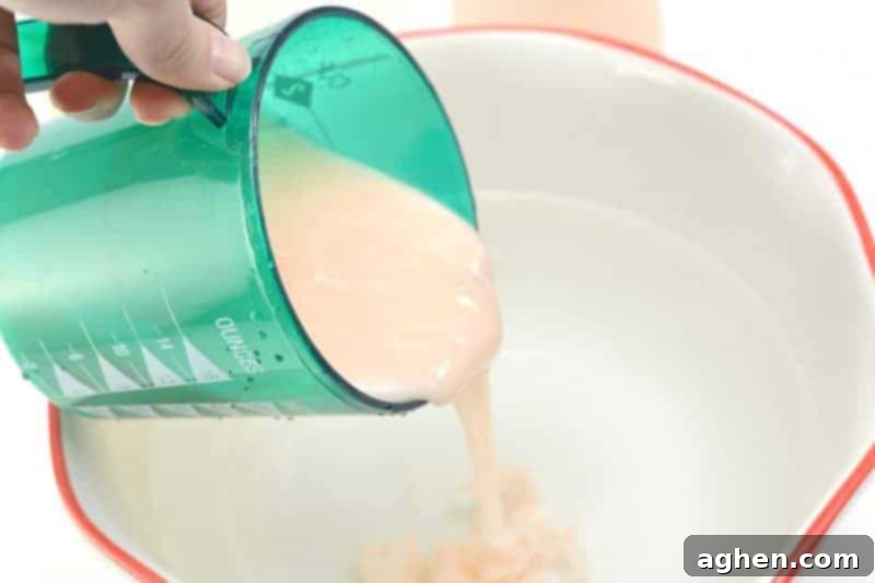 Hair conditioner being squeezed into the water and vinegar mixture, ready for stirring.