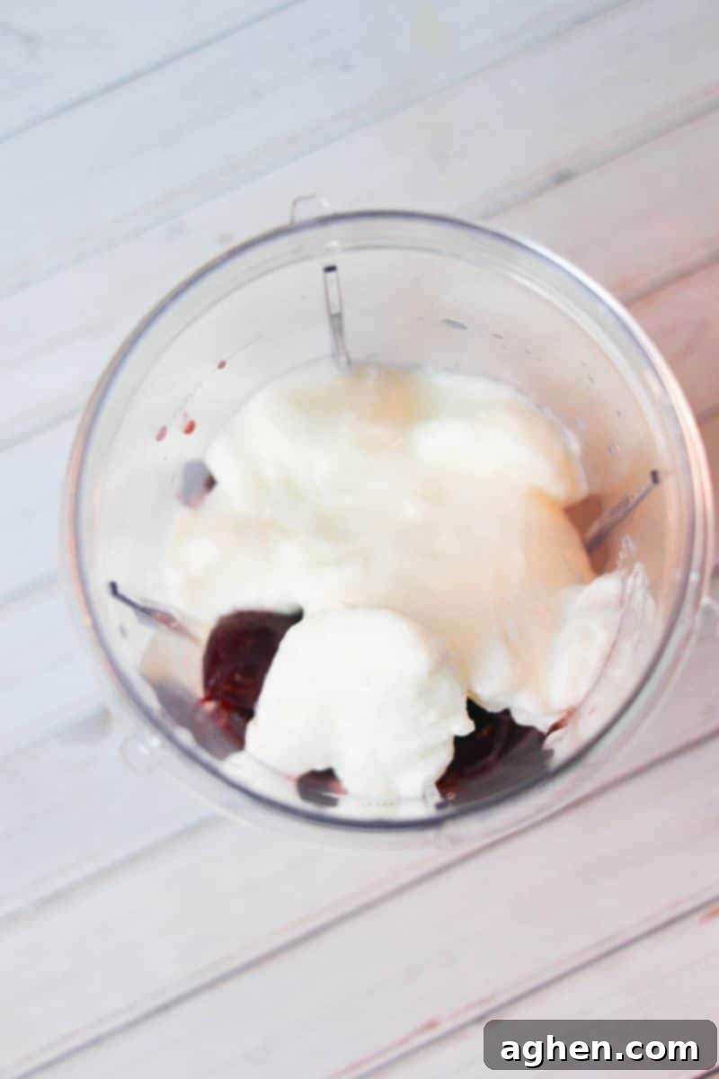 Adding Yogurt to the Blender for a Creamy Pineapple Cherry Smoothie