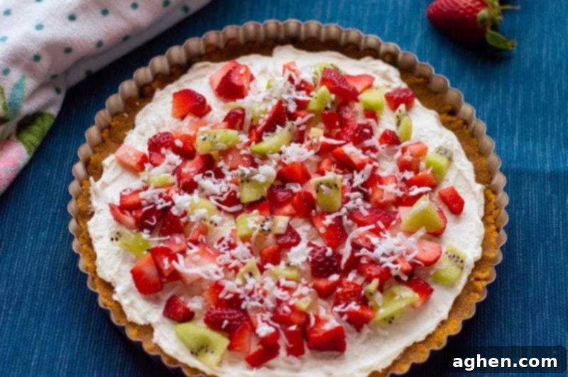 A beautifully decorated no-bake fruit pizza with cream cheese and fresh fruit on top of a homemade graham cracker crust, perfect for summer.