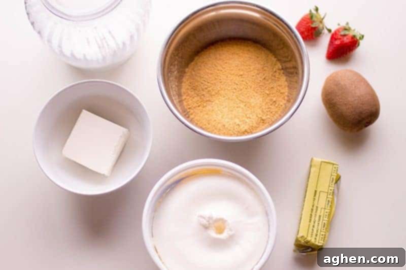 A flat lay of all the ingredients needed to make a no bake fruit pizza: graham cracker crumbs, butter, cream cheese, sugar, whipped topping, and assorted fresh fruit.