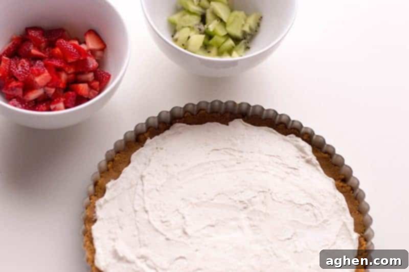 Mixing cream cheese, sugar, and whipped topping to create the smooth, creamy filling for the fruit pizza.