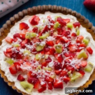 A beautifully decorated no-bake fruit pizza with cream cheese and fresh fruit on top of a homemade graham cracker crust, perfect for summer.