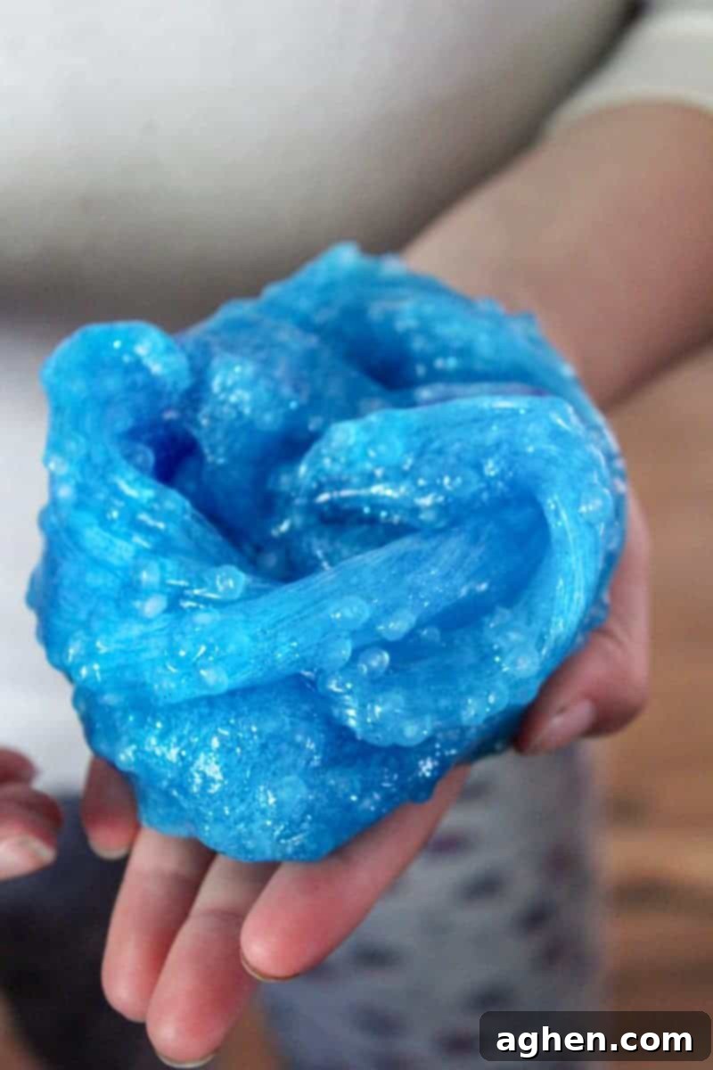 The fully completed borax-free ocean slime, featuring embedded plastic fish and fishbowl beads, elegantly stretched and ready for interactive sensory play.