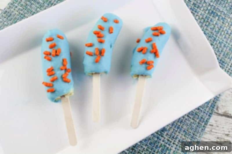 Three banana halves coated in blue chocolate with orange fish sprinkles, evoking an ocean theme.