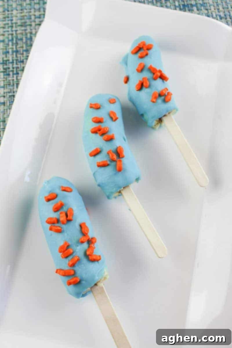 A serving platter filled with completed Under the Sea Banana Treats, each coated in blue chocolate and fish sprinkles.