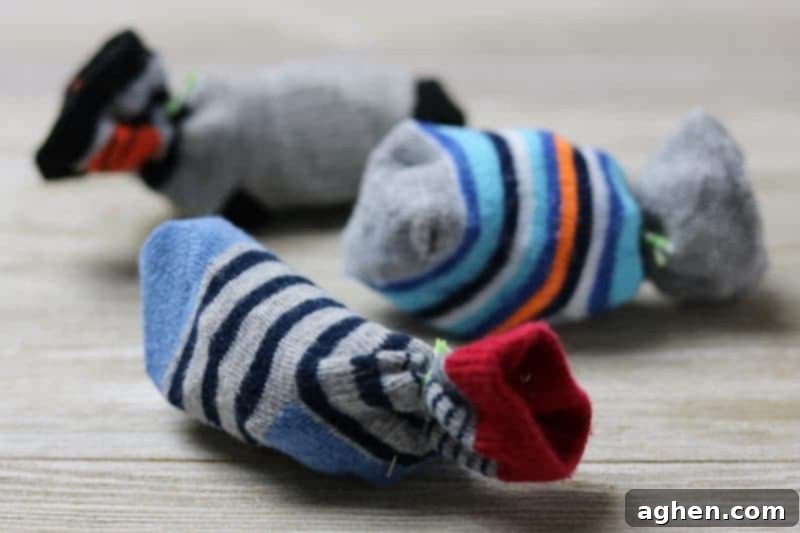 Hands demonstrating how to make a simple DIY cat toy using a baby sock and crumpled paper.