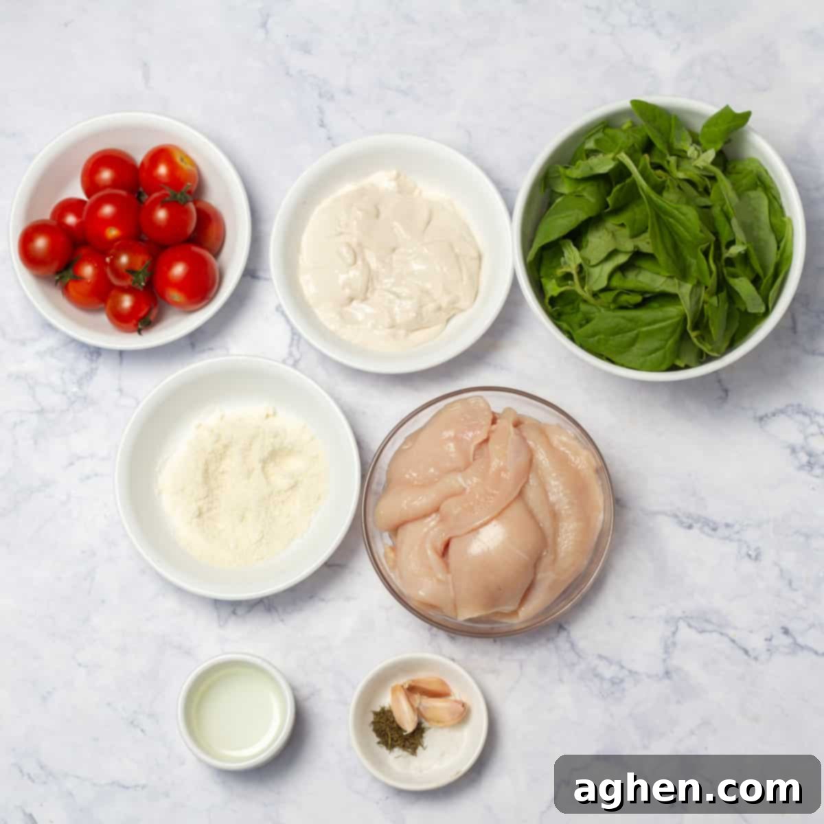 Tuscan chicken ingredients of chicken breast, spinach, cherry tomatoes, fat-free Greek yogurt, parmesan cheese, Herbs de Provence, garlic, and salt in separate dishes. 