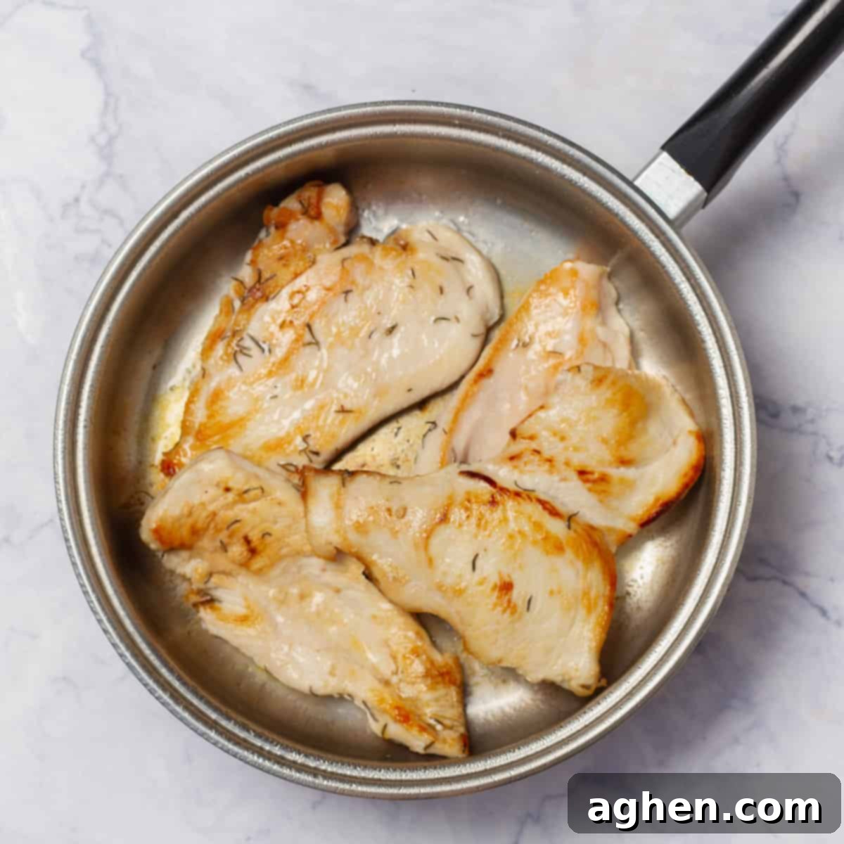 Grilling seasoned chicken breasts in a pan. 
