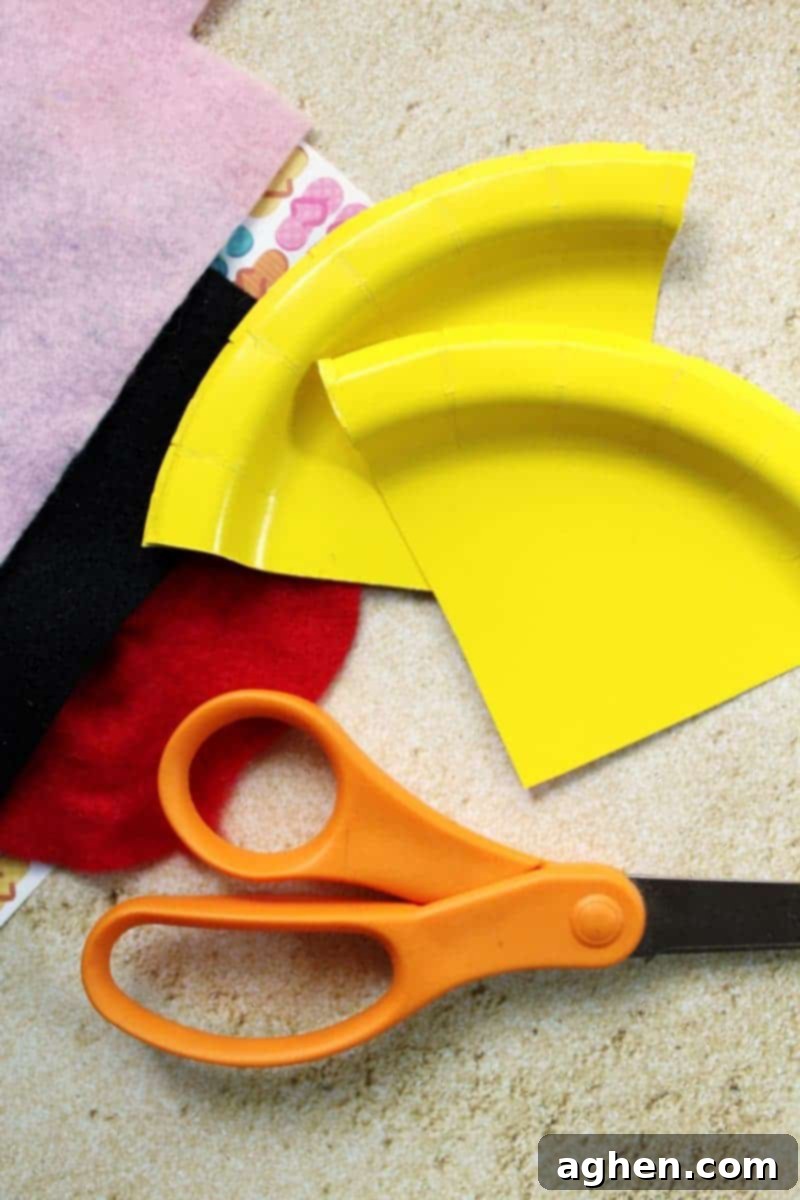DIY Paper Plate Fish 4 Step-by-step image demonstrating how an adult cuts wedges from the edge of a yellow paper plate to form fish fins.