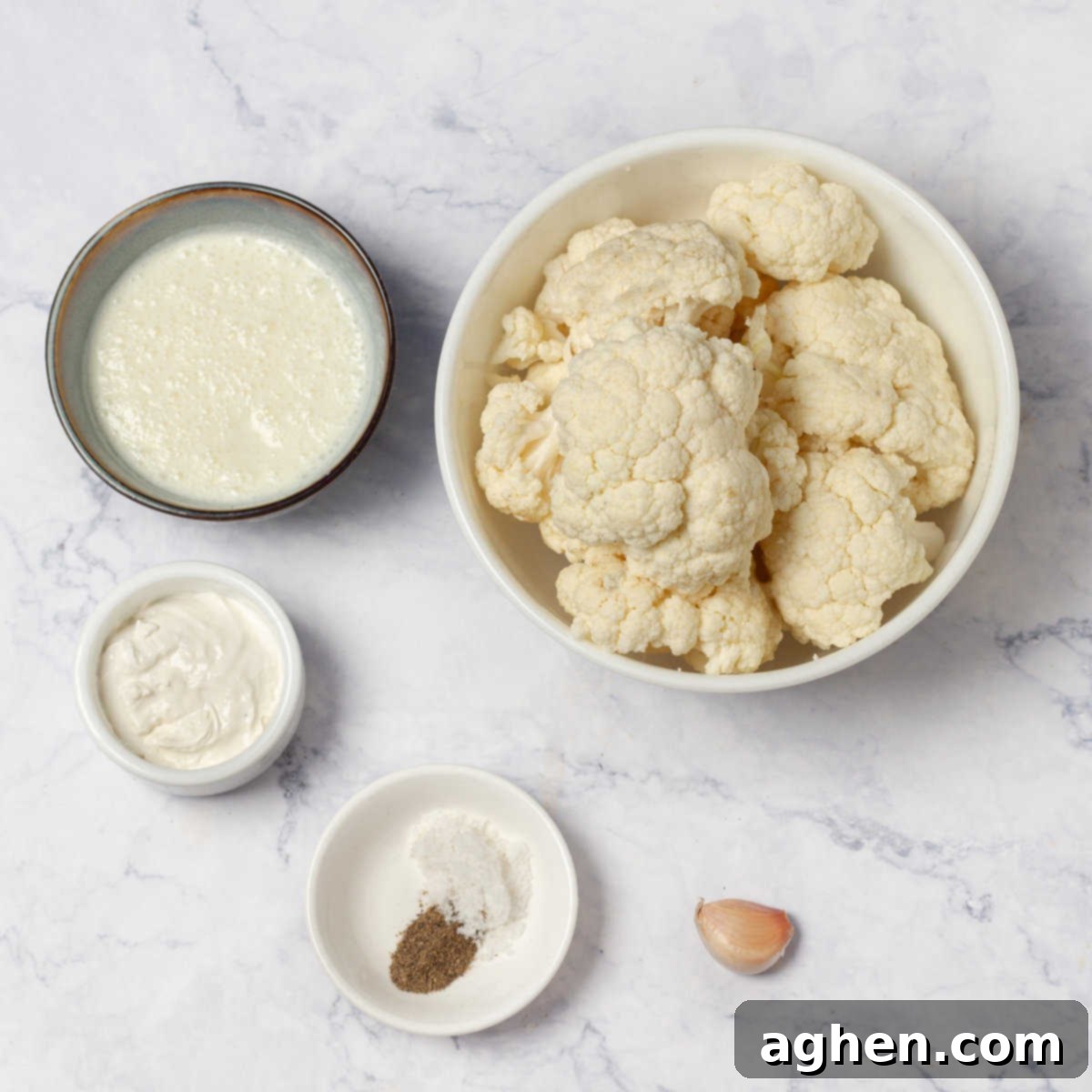 The Zero Point Mashed Cauliflower I Make On Repeat 3 Ingredients for Mashed Cauliflower laid out on a kitchen counter, including a whole cauliflower, yogurt, milk, and garlic.