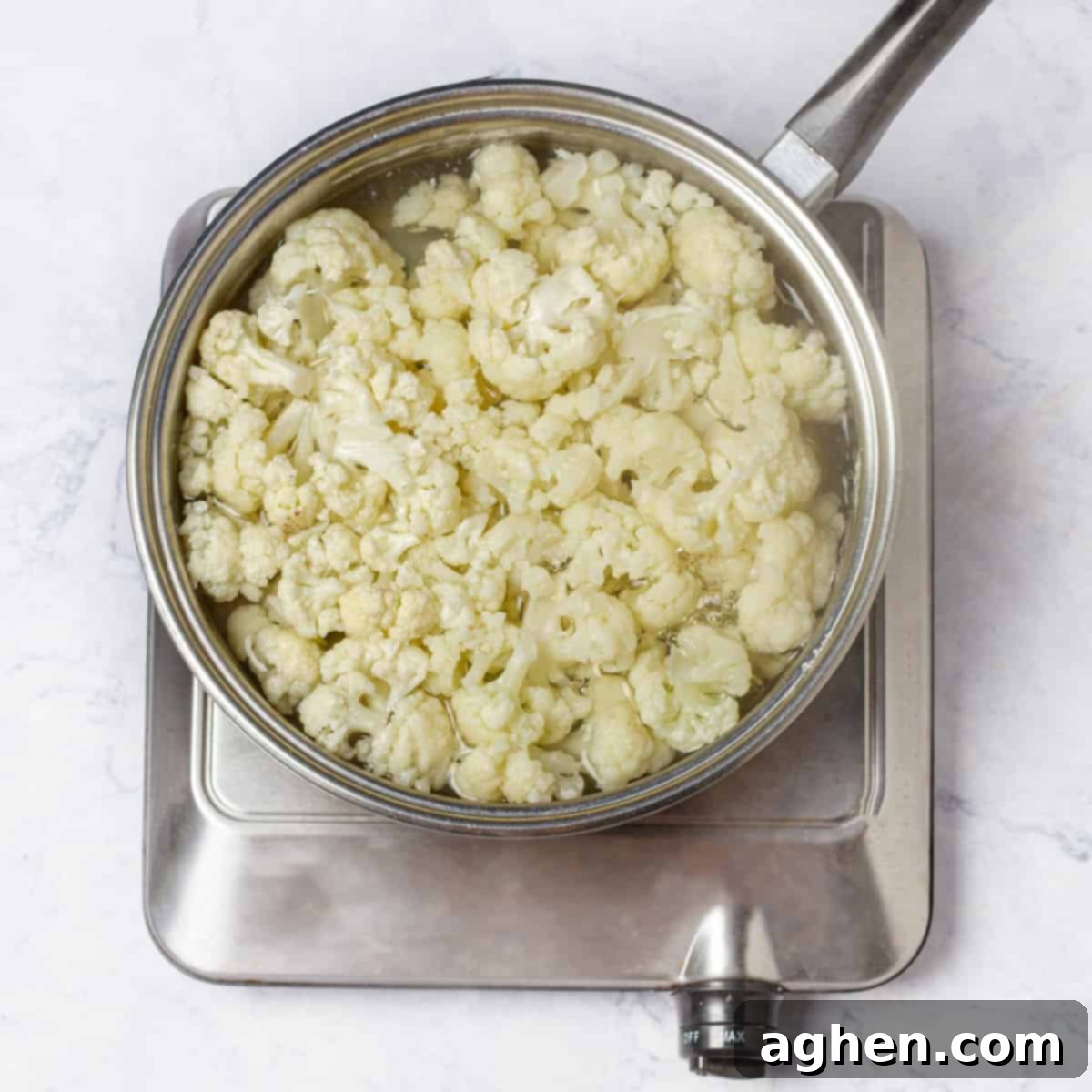 The Zero Point Mashed Cauliflower I Make On Repeat 4 Cauliflower florets boiling in a pot over medium heat on a stovetop, creating steam.