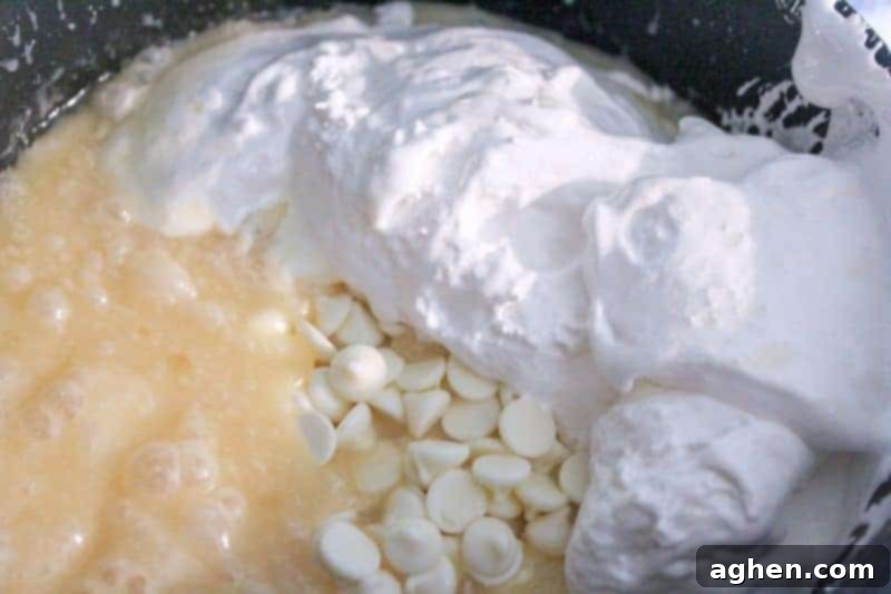 Step 2: White chocolate chips and marshmallow creme are added to the hot sugar mixture for the creamy fudge base.