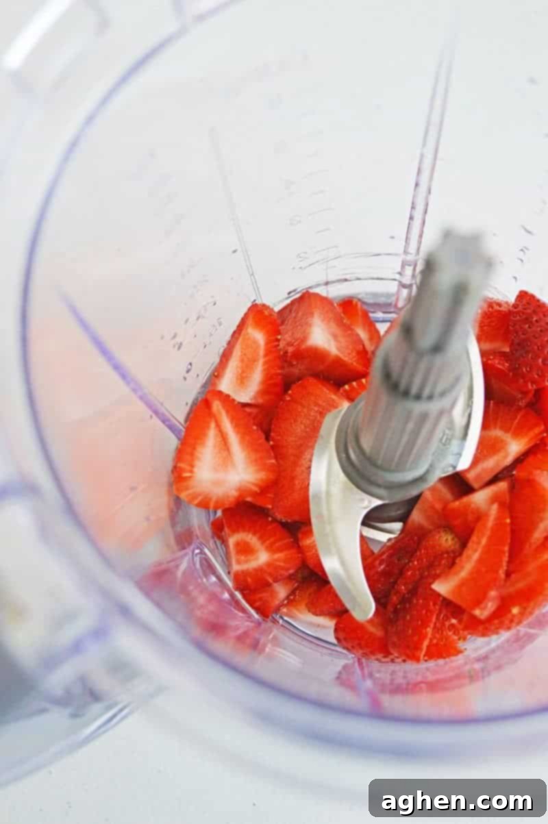 Strawberries being added to a blender for strawberry lemonade jello shots.