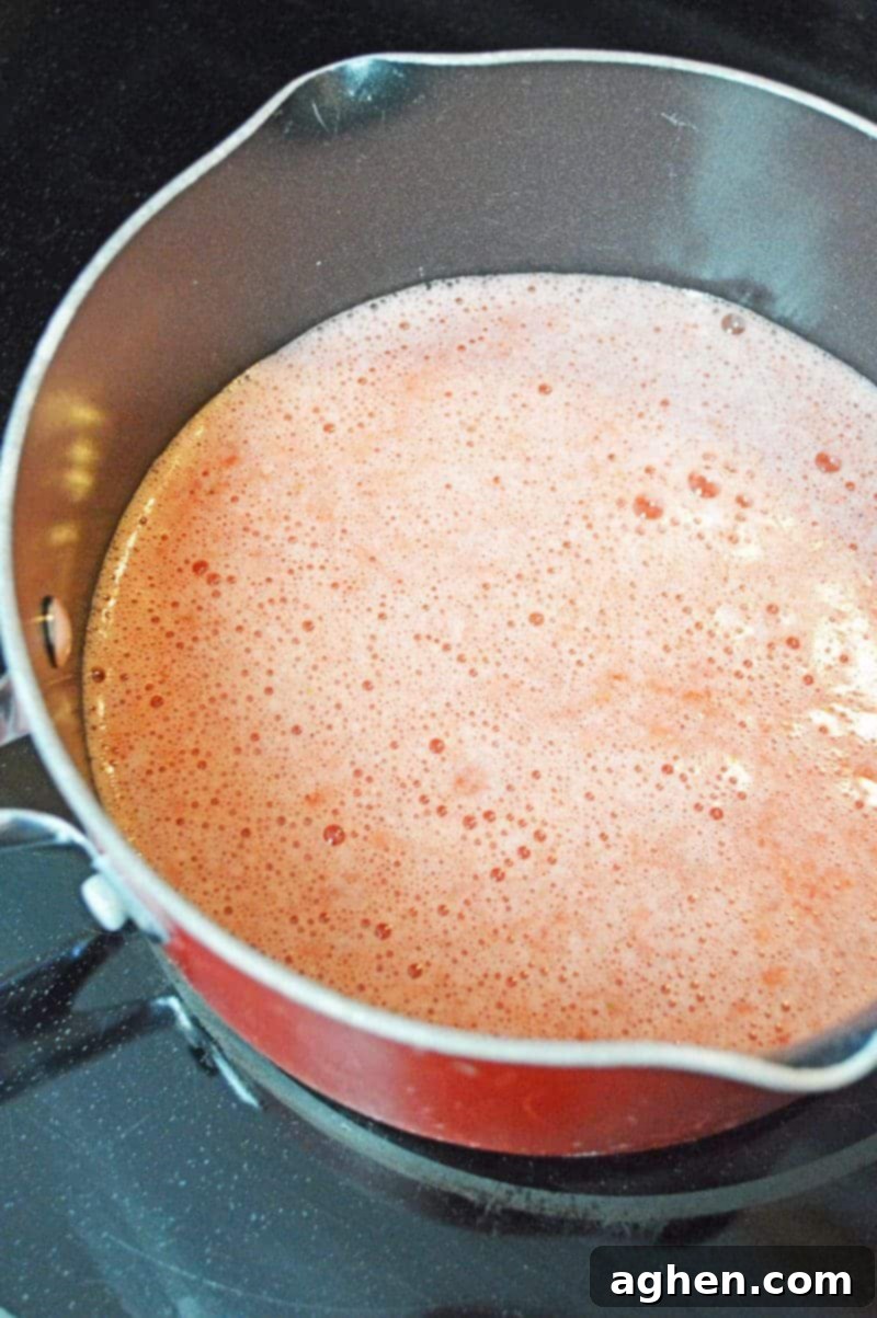 Strawberry lemonade jello shot mixture heating in a saucepan.
