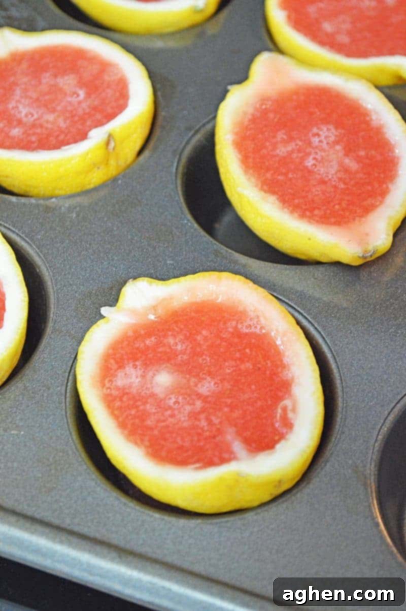 Pouring jello mixture into hollowed lemon halves in a muffin tin.