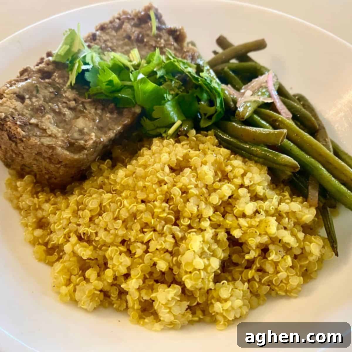 Hearty and flavorful Vegan Lentil Loaf on a plate with vibrant green beans and fluffy quinoa, showcasing a perfect texture.