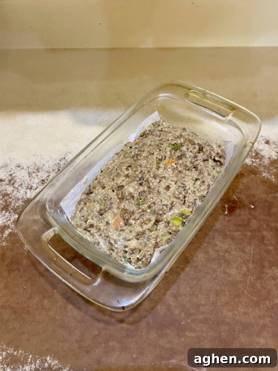 The lentil loaf mixture firmly pressed into a parchment-lined bread pan, ready for baking at 375 degrees F.
