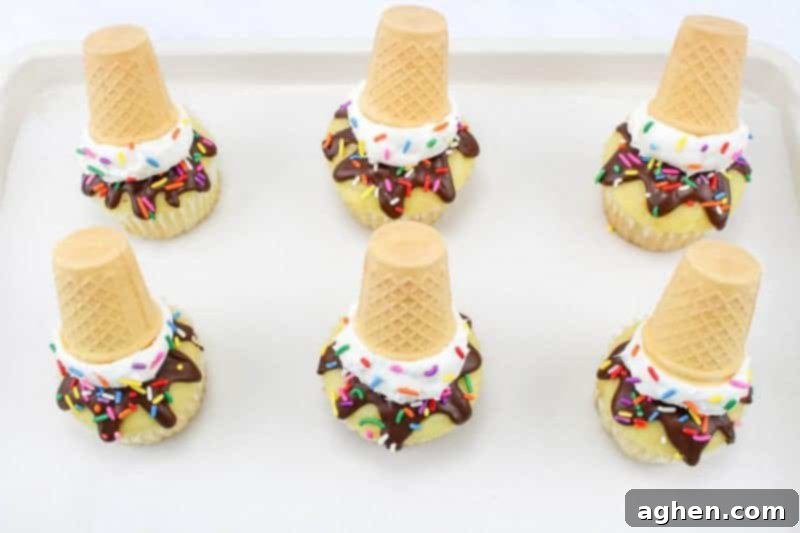 Process shot: A small cookie scoop adding white frosting on top of a chocolate-dipped cupcake.