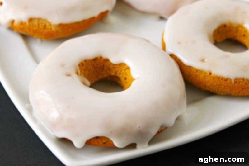 Warm baked pumpkin donuts with vanilla glaze, stacked on a cooling rack, ready to be enjoyed.