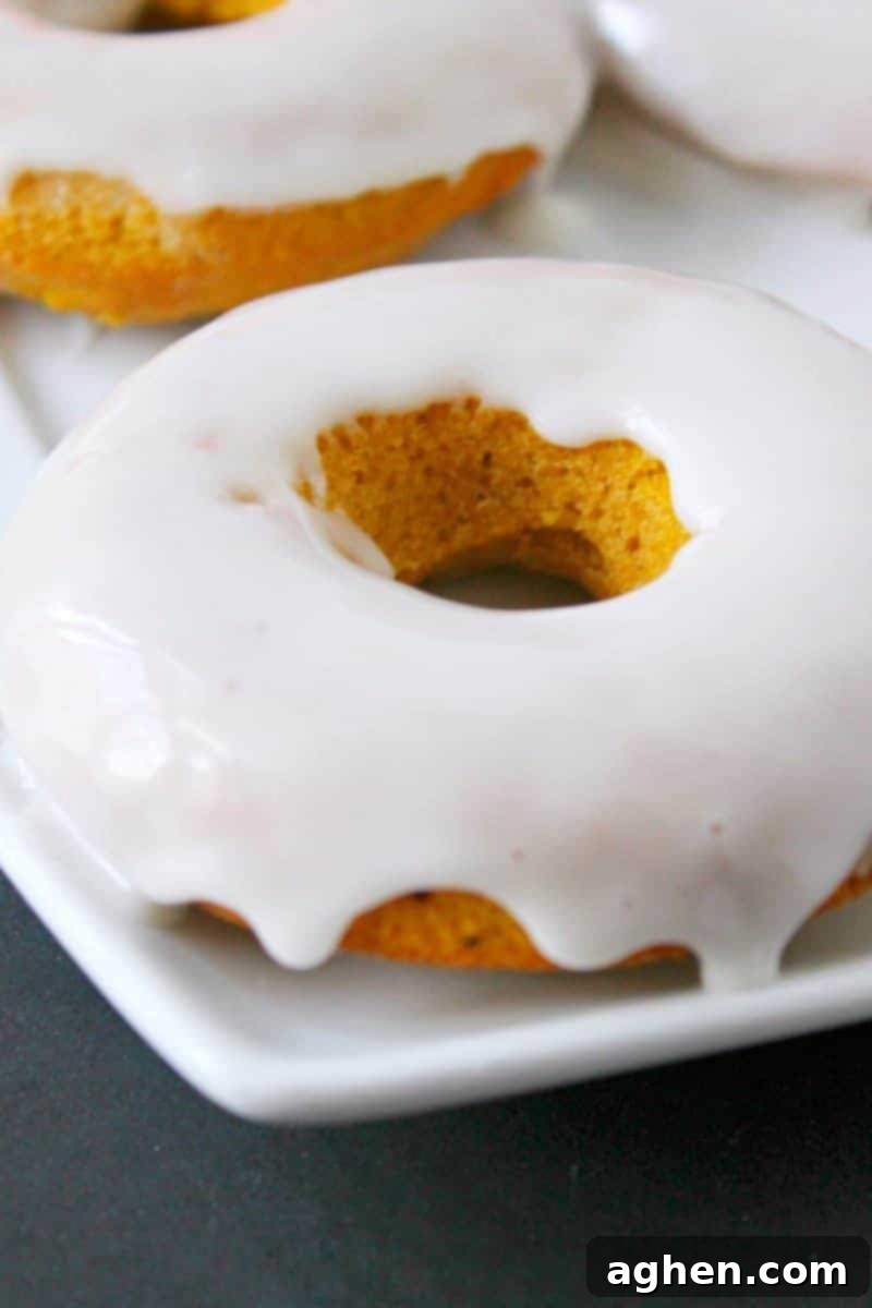 Close-up of a single glazed baked pumpkin donut, showcasing its fluffy texture and perfect coating.