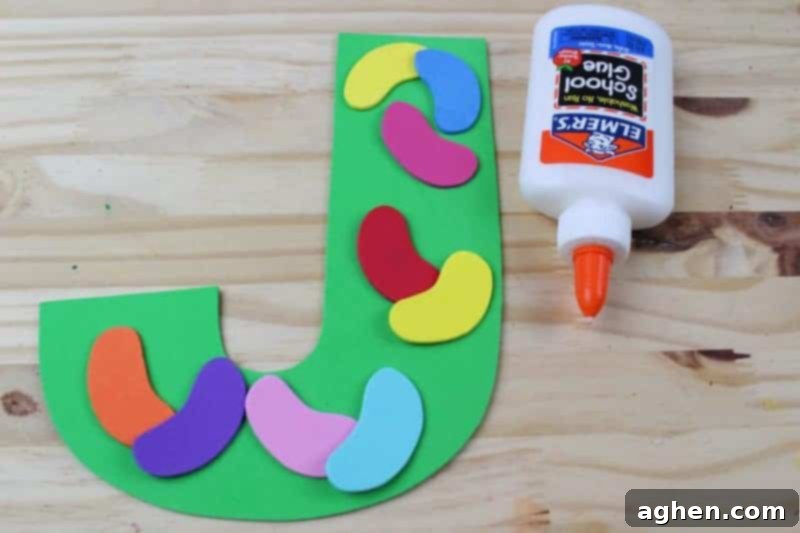 Apply glue and attach the colorful jelly bean shapes onto the letter J.
