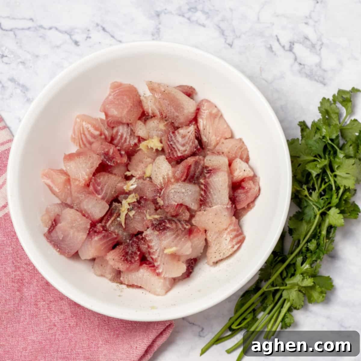 Fish cubes seasoned with freshly crushed garlic, salt, and black pepper, ready for the citrus marinade to infuse flavor.