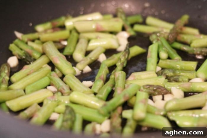 Asparagus, Garlic, and Olive Oil sizzling in a large skillet.