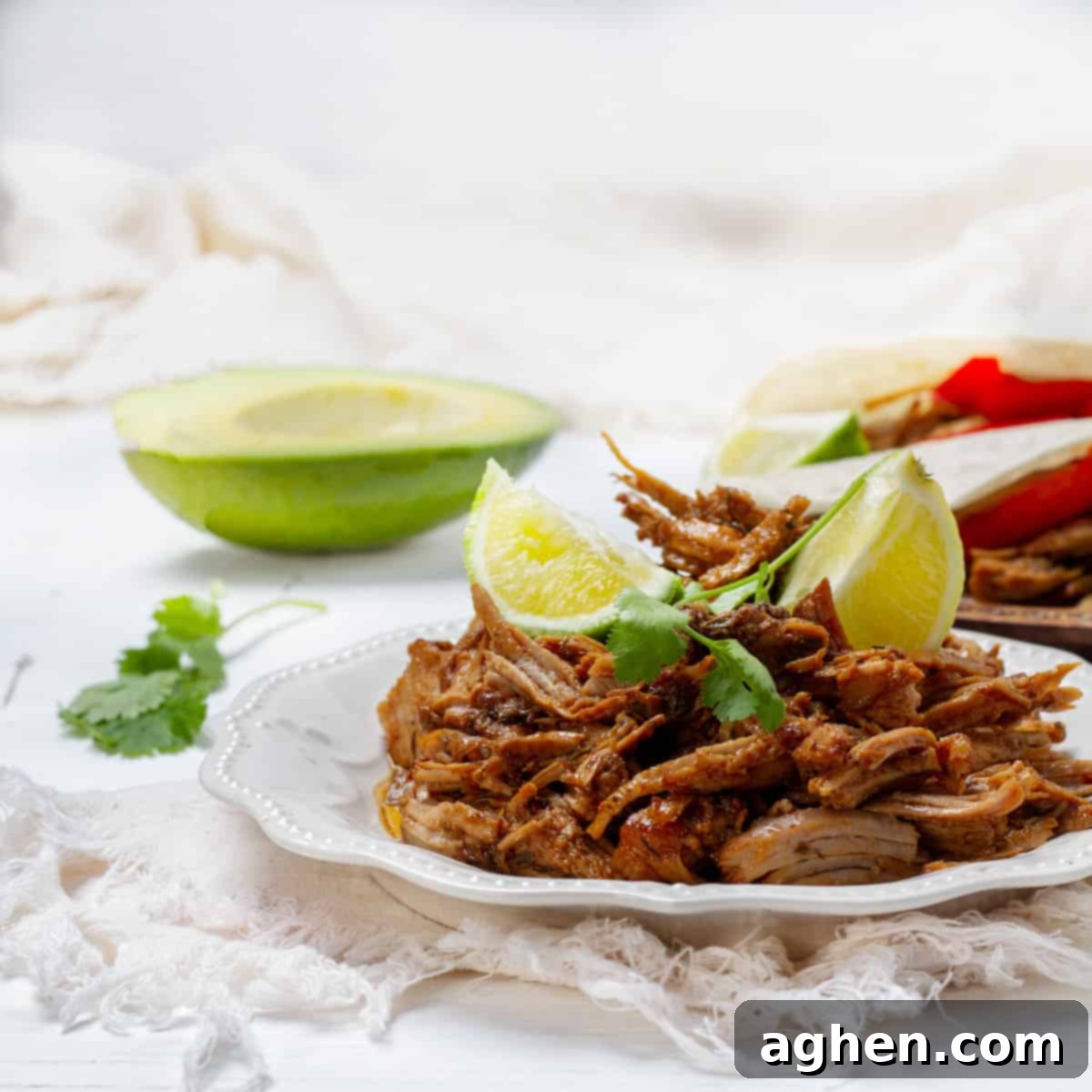 Carnitas platted with lemon slice and avocados