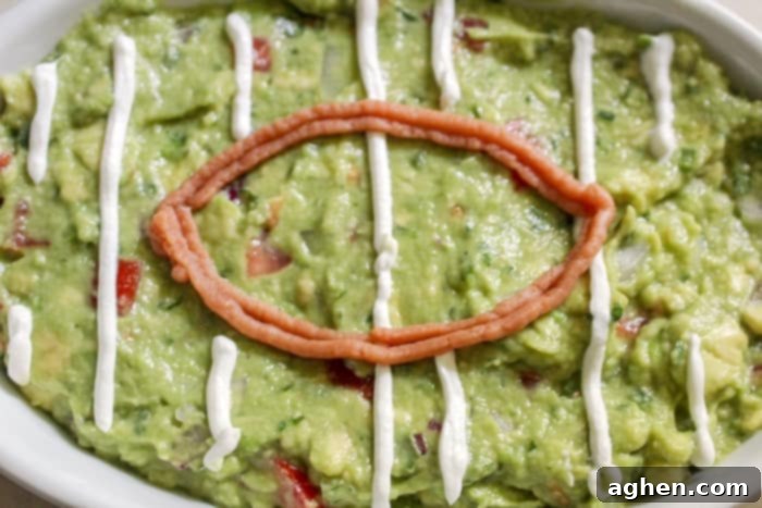 Piping sour cream onto guacamole to create yard lines for a football field design, showing the in-process steps for easy football guacamole.