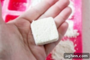 hand holding a dishwasher tablet, with mold in the background