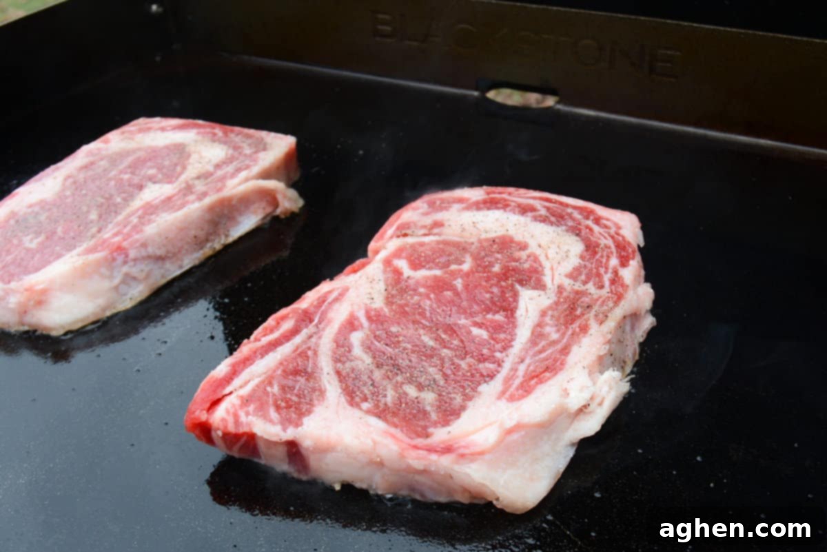 Mastering Steak on the Blackstone Griddle 5 seasoned ribeye cooking on a hot blackstone