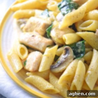 One Pot Creamy Spinach Chicken Pasta Recipe in a white bowl with a fork