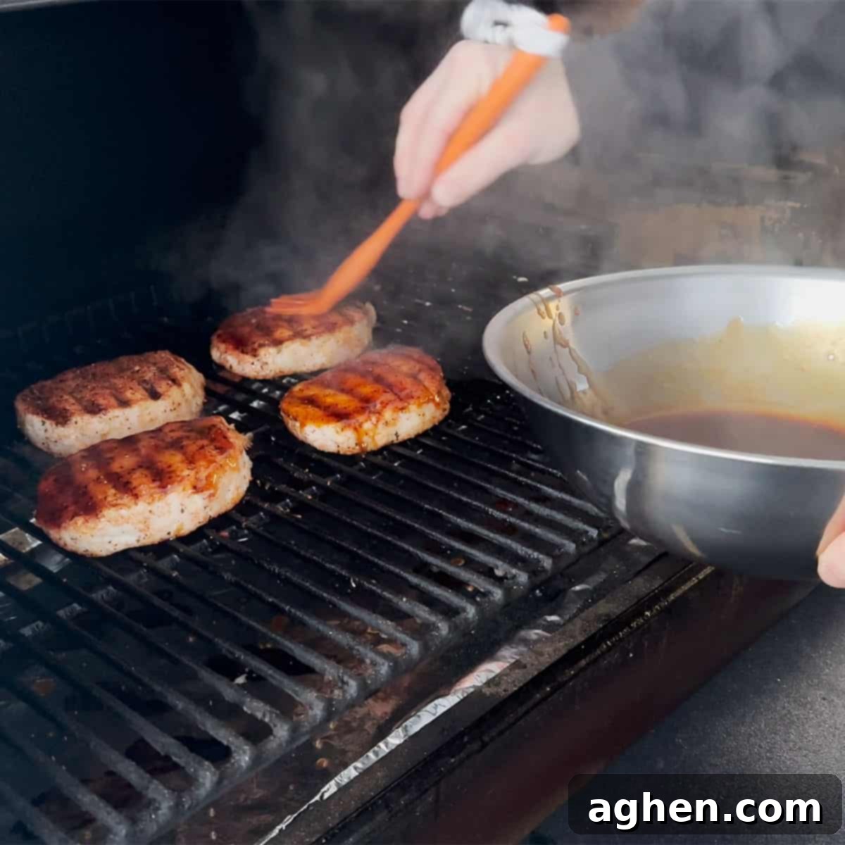 Smoked pork chops being brushed with root beer glaze on the smoker