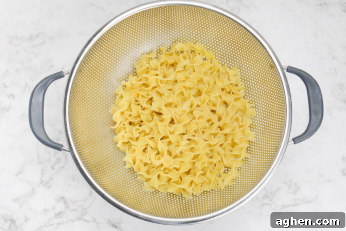 Heartwarming Chicken Noodle Bake 4 A silver collander with drained yellow noodles