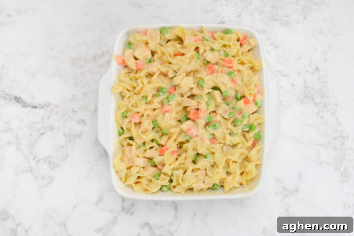 Heartwarming Chicken Noodle Bake 8 A white casserole dish is filled with the casserole ingredients before baking.
