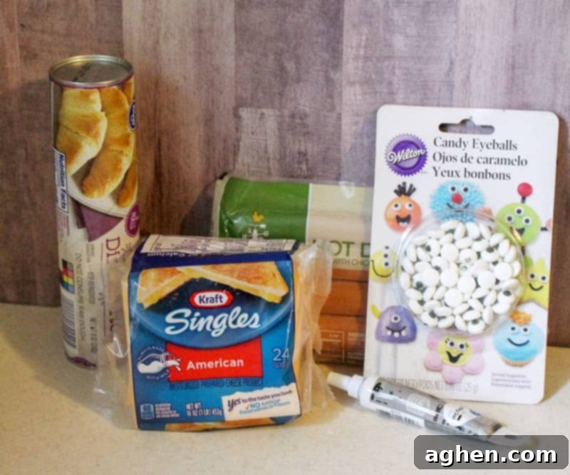 All the ingredients laid out for making mummy hot dogs: crescent roll dough, hot dogs, cheese slices, candy eyes, and decorating gel.