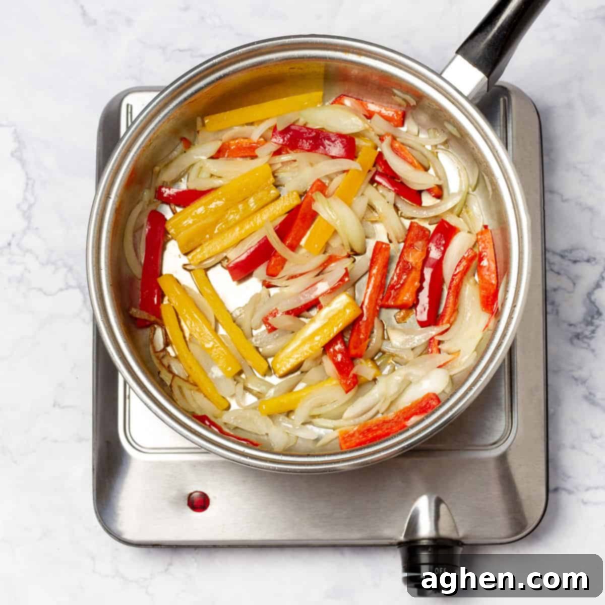 A Wok on flame with onions, carrots, and snow peas actively sautéing