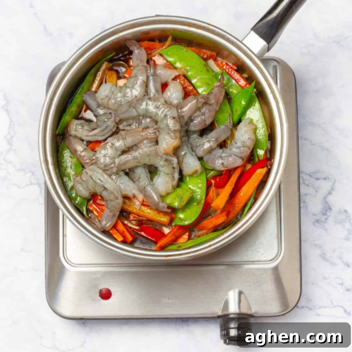 A wok filled with shrimp and vegetables, mid-cooking process