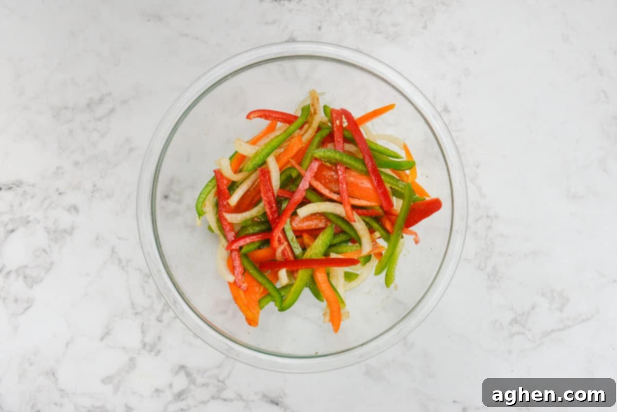 A bowl filled with red, orange, and green bell pepper strips and sliced onions. 