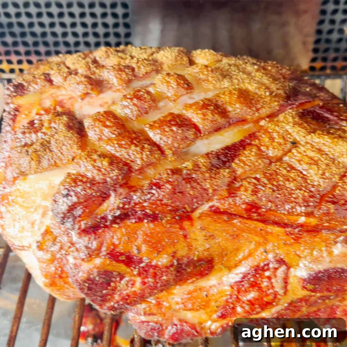 Signature Traeger Pulled Pork 6 A pork butt smoking on the grates of a Traeger grill, fat side up, with visible smoke.