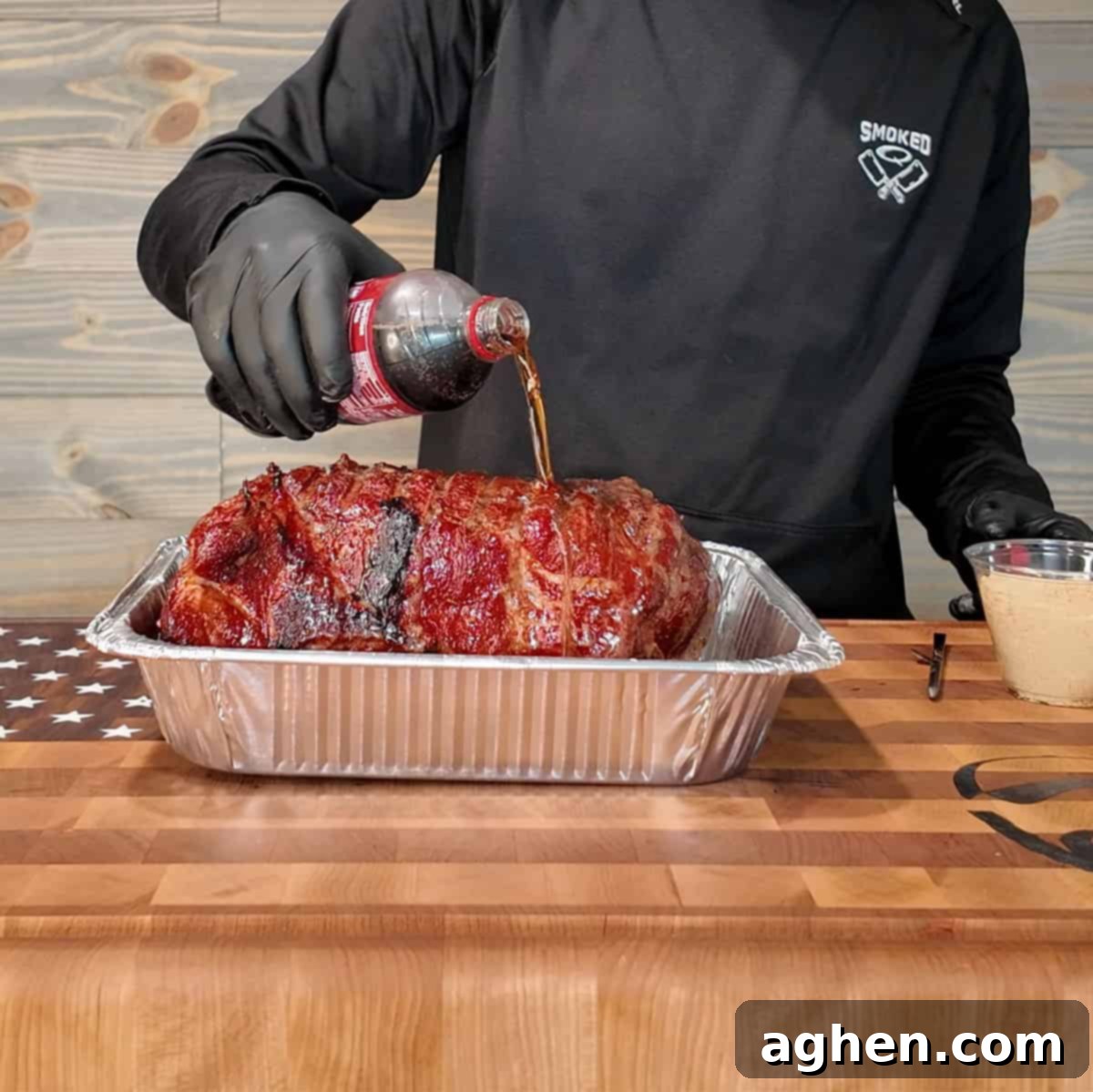 Signature Traeger Pulled Pork 7 A pork butt in an aluminum pan, wrapped in foil, cooking on a smoker.