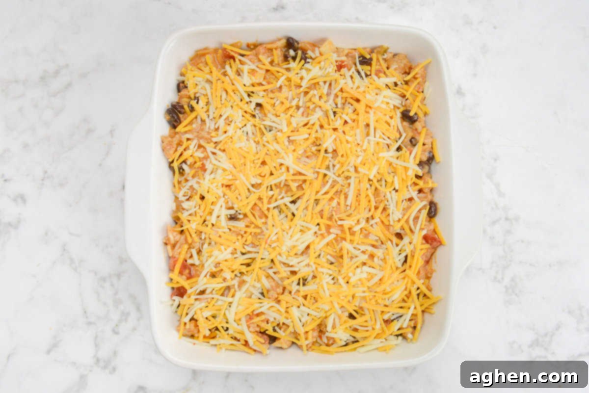 Indulge in Doritos Casserole on Weight Watchers! 11 A white square baking dish filled with the casserole mixture and topped entirely with orange and white shredded cheese.