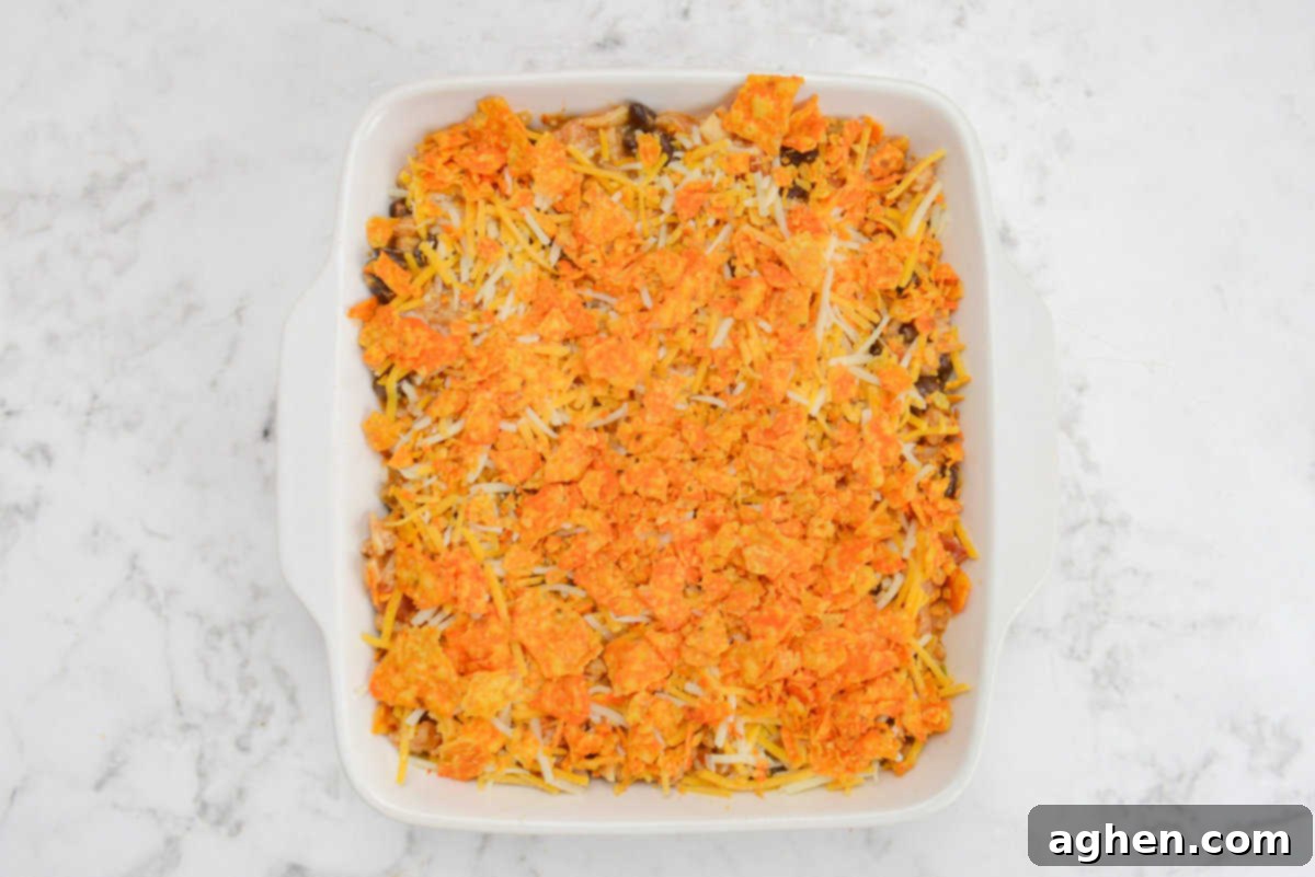 Indulge in Doritos Casserole on Weight Watchers! 12 A white square baking dish filled with casserole mixture is topped with bright orange Doritos pieces