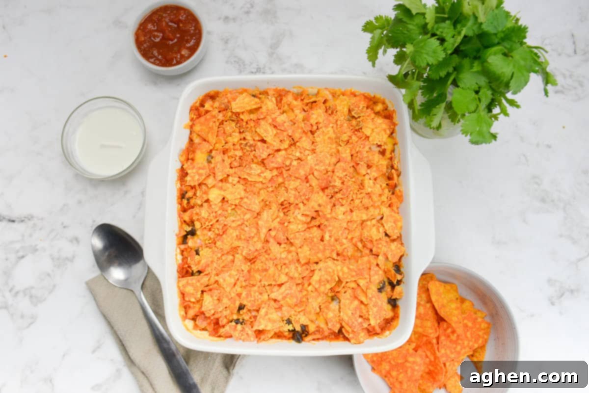 Indulge in Doritos Casserole on Weight Watchers! 13 A white square baking dish is shown with the now cooked casserole. To the side are a serving spoon, bunch of cilantro and bowls filled with Doritos, Greek Yogurt and salsa.