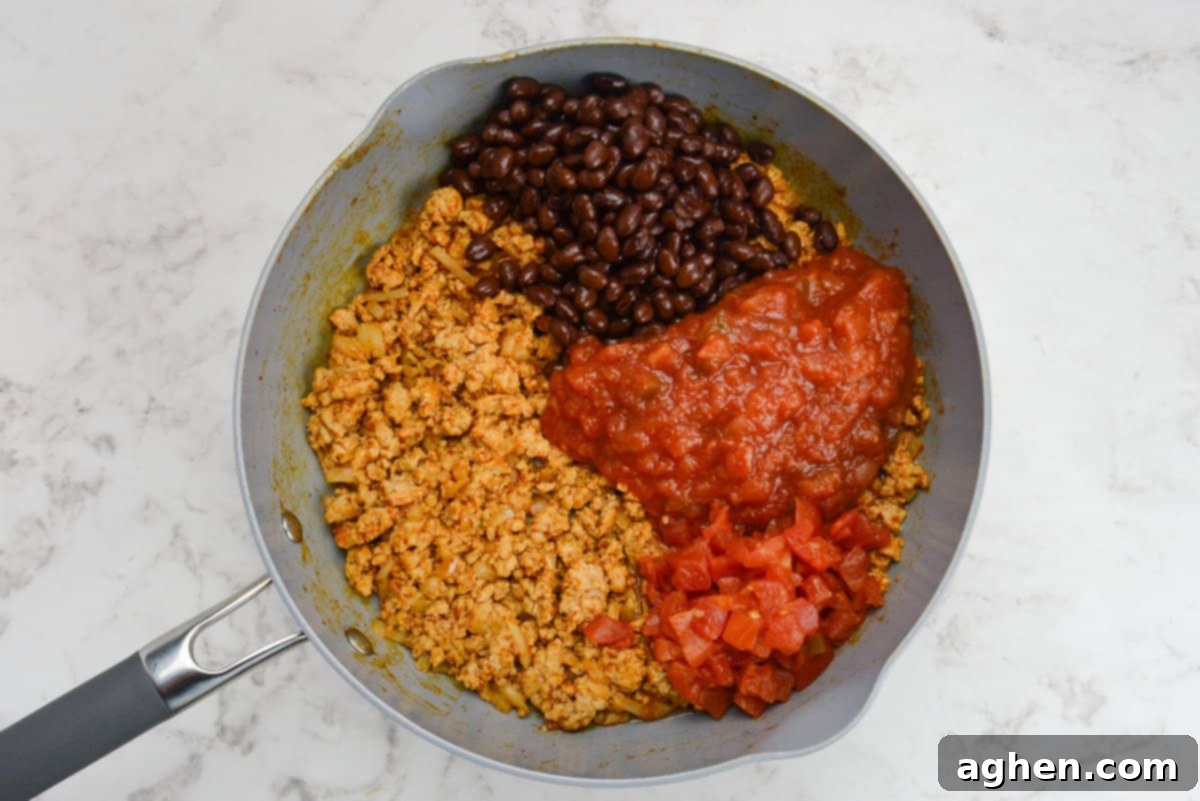 Indulge in Doritos Casserole on Weight Watchers! 6 A skillet with ground chicken, black beans, salsa, and diced tomatoes that are not mixed together.