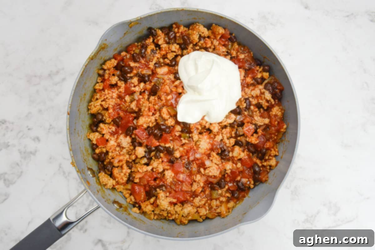Indulge in Doritos Casserole on Weight Watchers! 7 A skillet with casserole filling and a scoop of Greek yogurt