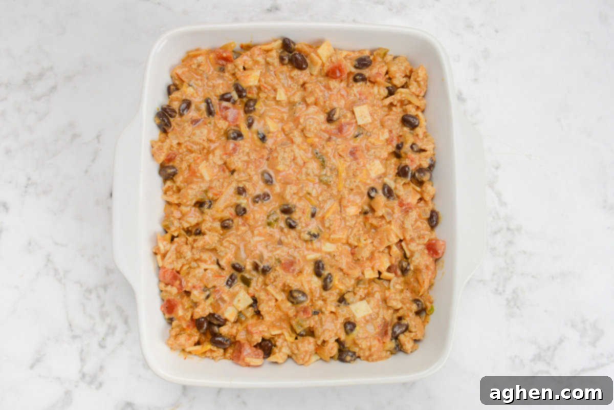 Indulge in Doritos Casserole on Weight Watchers! 10 A white square baking dish filled with the casserole mixture is on a white marble surface.