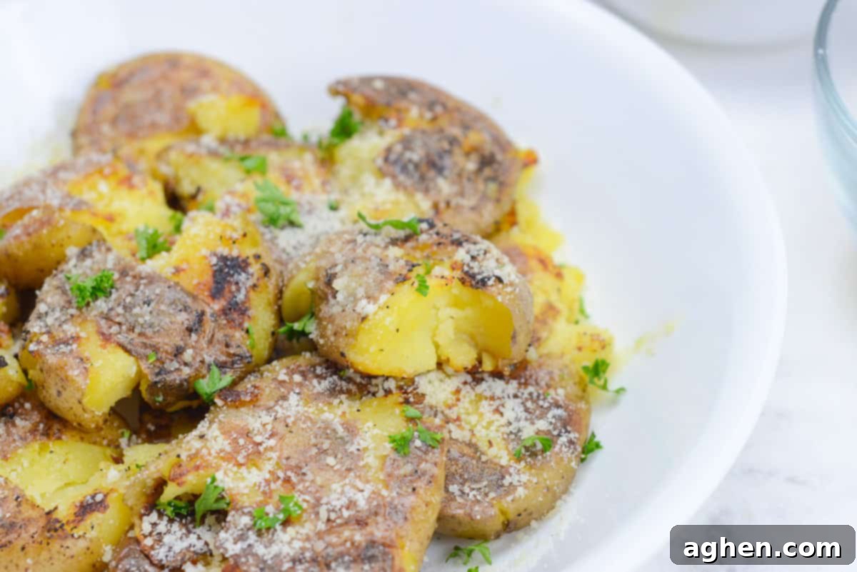 Crispy Blackstone Smashed Potatoes 12 closeup on blackstone smashed potatoes, coated in grated parmesan cheese and sprinkled with parsley.