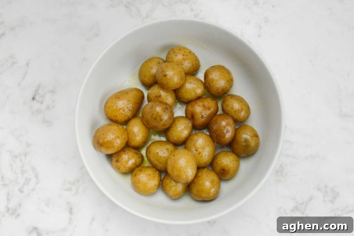 Crispy Blackstone Smashed Potatoes 7 baby potatoes covered in olive oil and butter, sitting in a white bowl
