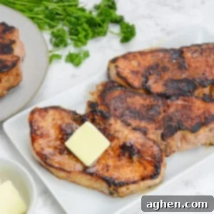 Blackstone'da Domuz Pirzolası 7 Kolay Adımda 11 finished blackstone pork chops, plated on a white platter and topped with butter